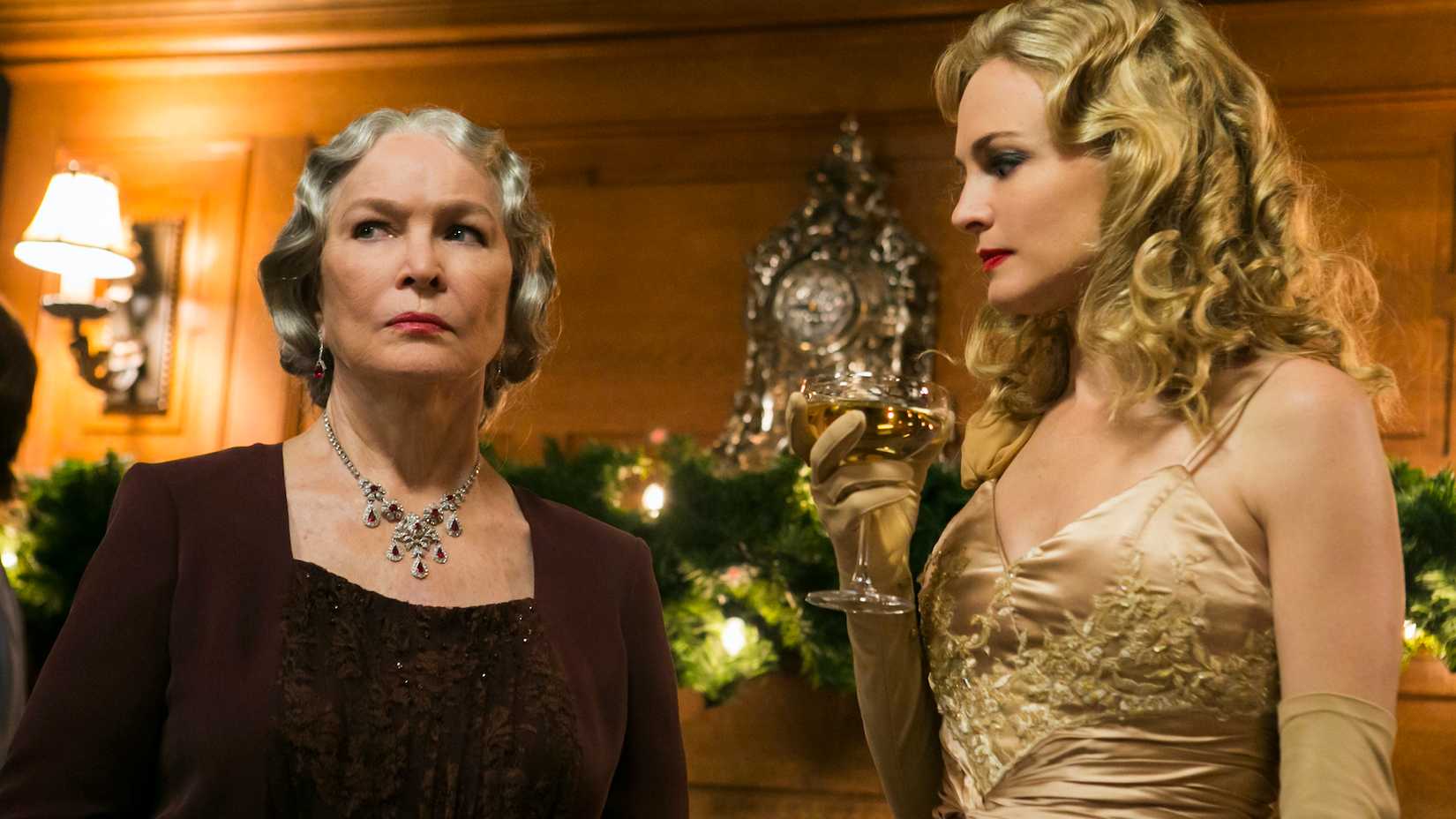 Ellen Burstyn and Heather Graham wearing formal attire in a fancy manor room